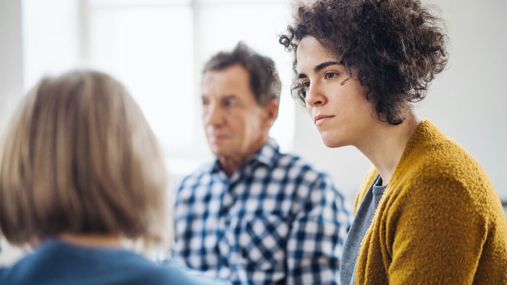 3 Menschen unterhalten sich in einem therapeutischen Setting